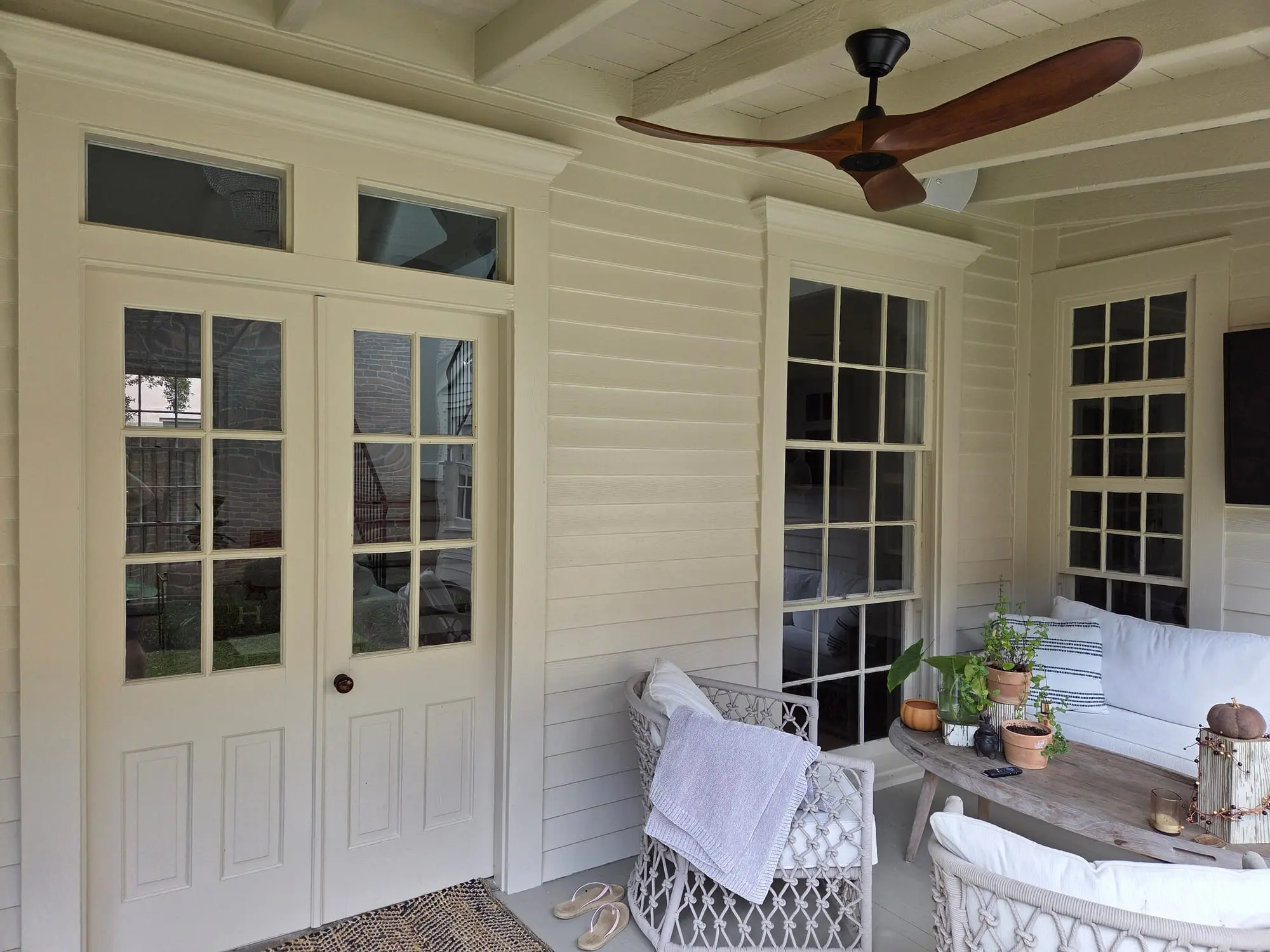 Clean French doors with transom windows and divided-light windows on a covered porch