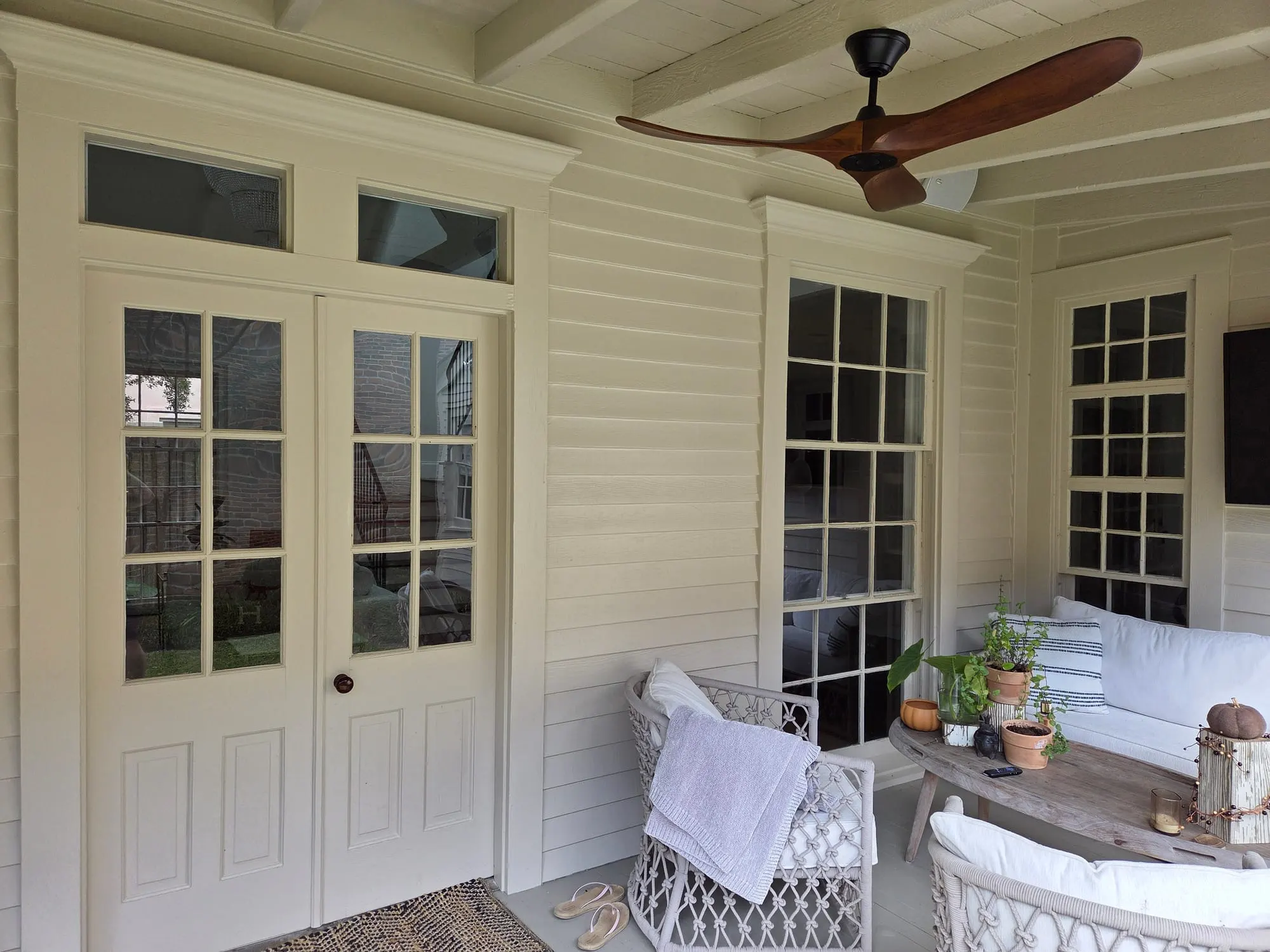 Clean French doors with transom windows and divided-light windows on a covered porch